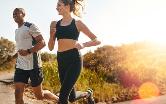 Pareja corriendo por un sendero al sol de la mañana