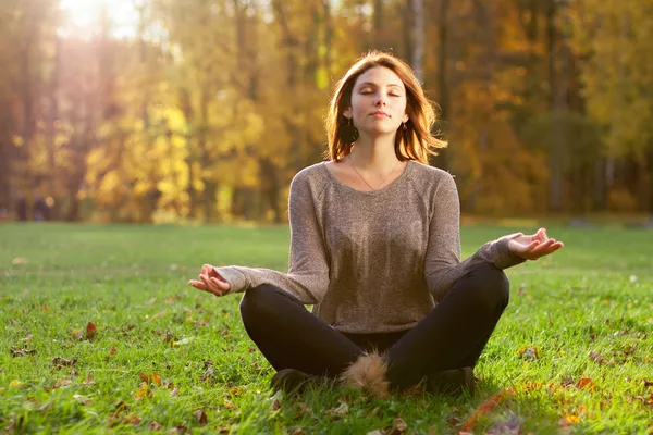 Mujer meditando en un campo al atardecer